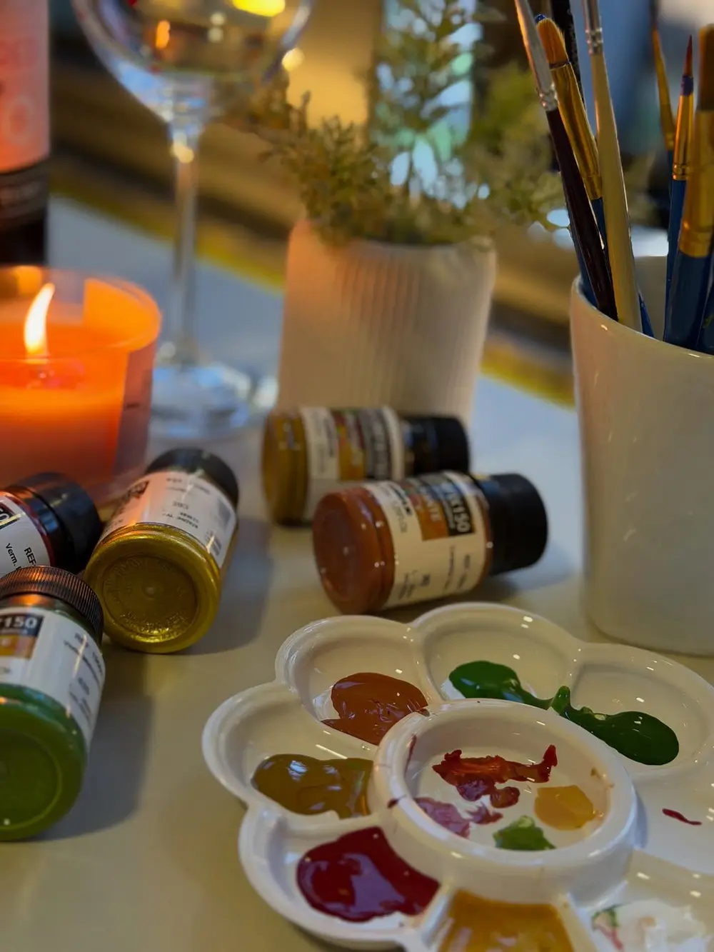Taça sendo pintada no ateliê, com a paleta de tintas ao lado